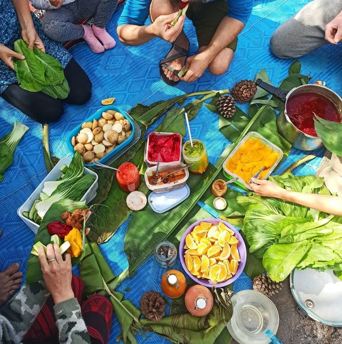 friends eating outdoor with leaves instead of plates